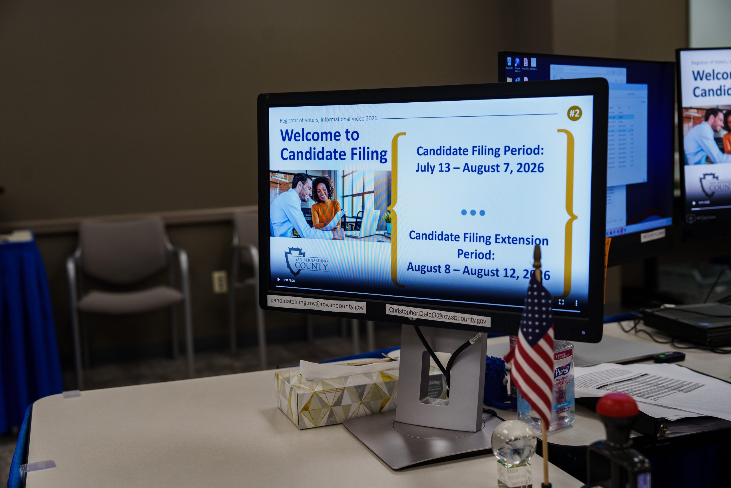 A computer monitor shows information about the candidate filing period from July 13 to August 7, 2026, and the extension period from August 8 to August 12, 2026.