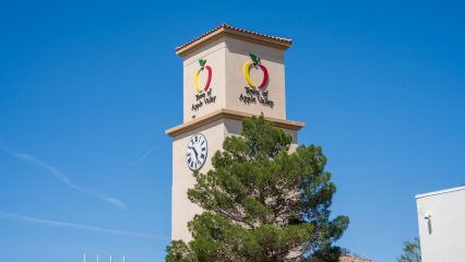 A clock tower displaying the Town of Apple Valley logo. A tree is partially covering the tower.