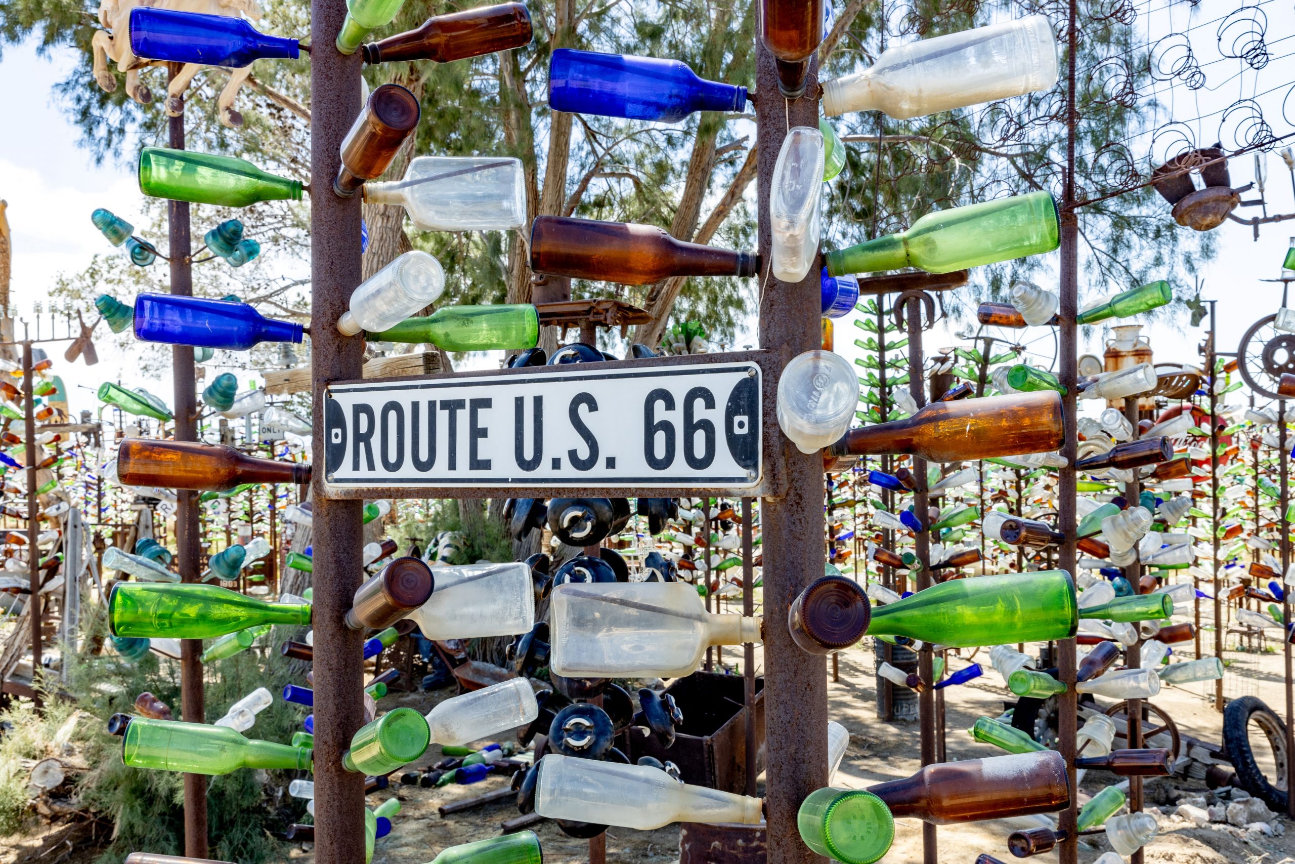 Colorful glass bottles arranged on old metal pipes and tree limbs