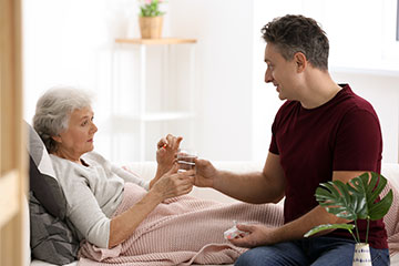 Man giving medication to elderly woman