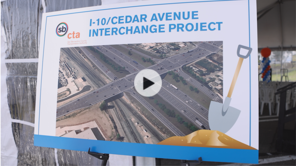 A closeup photo of a map of the I-10/Cedar Interchange Project with a shovel on an easel and people in the background.
