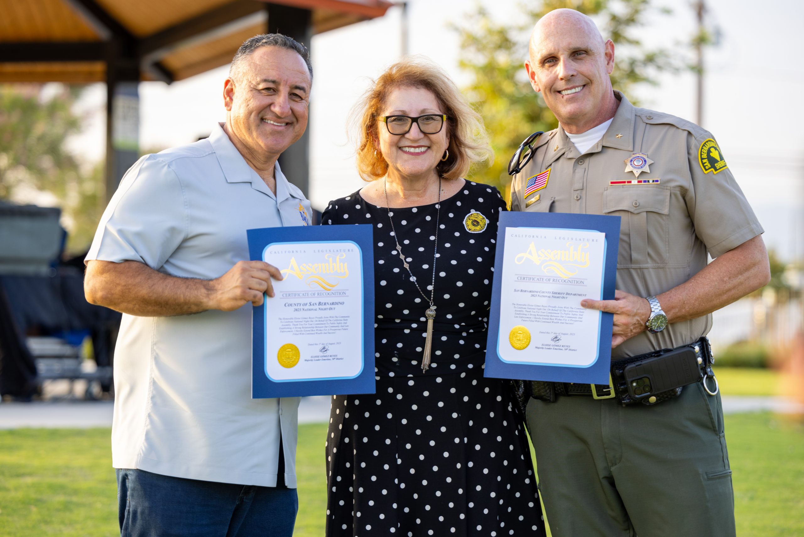California State Assembly Majority Leader Emeritus Elóise Gomez Reyes (center) presents, San Bernardino County Fifth District Supervisor Joe Baca, Jr. (left) and County Sheriff-Coroner Shannon D. Dicus (right) with Certificates of Recognition at the National Night Out event, Tuesday, Aug. 1, 2023, at Ayala Park in Bloomington.