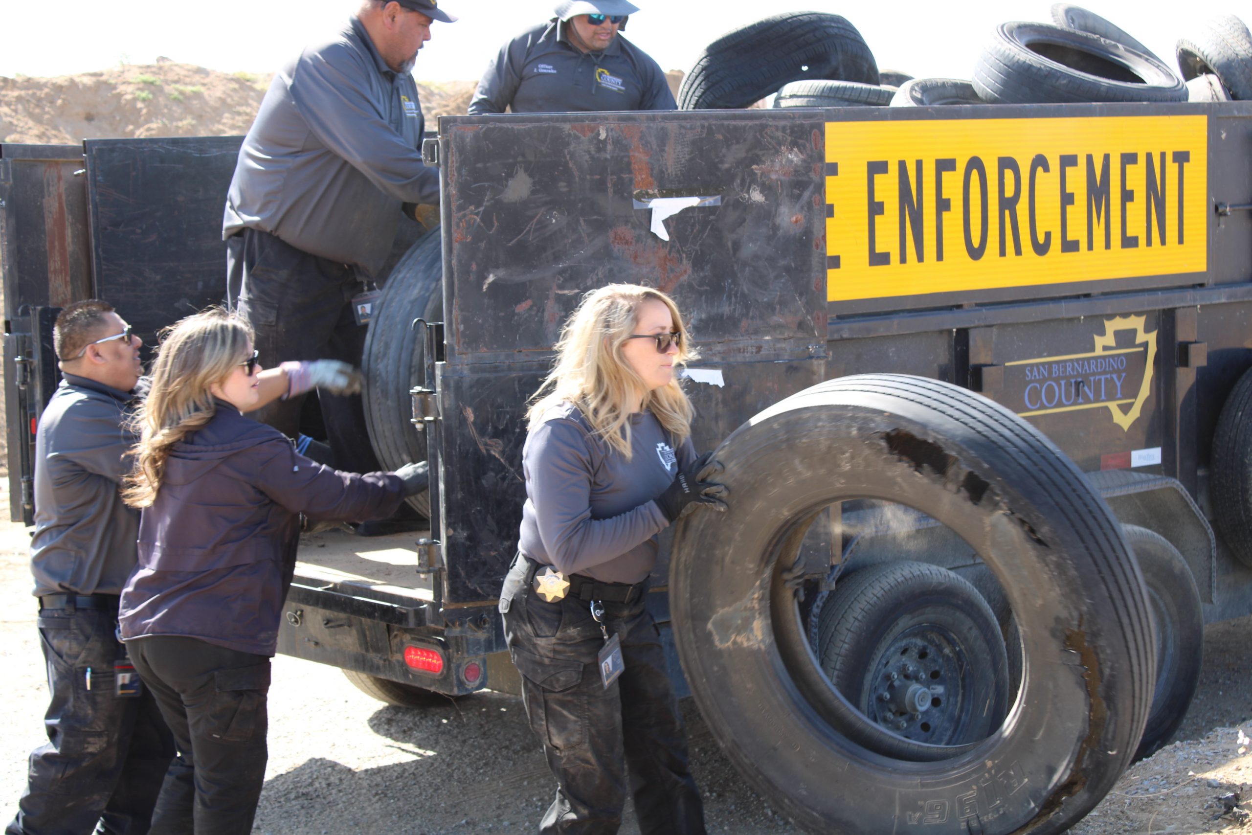 A photo of Code Enforcement staff loading up a truck in the desert with old tires.
