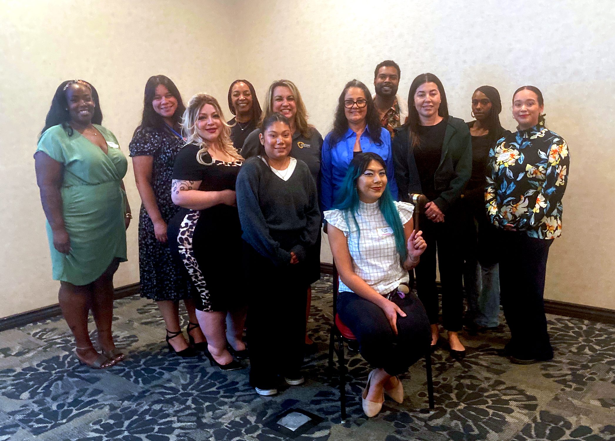 Eleven women and one man stand in a group posing for the camera.