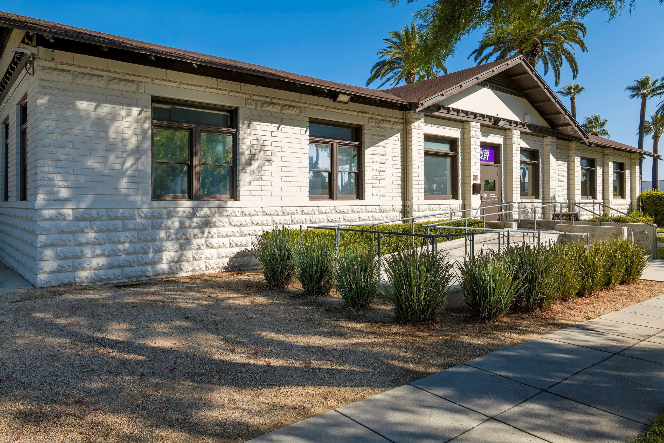 Exterior view of a single-story building with white brick walls and multiple windows.