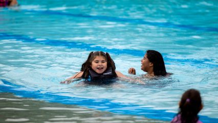 Three young girls are in a pool swimming.