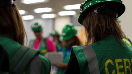 Participants wearing green helmets and vests with "CERT" written on them. The focus is on individuals in the foreground, with others blurred in the background.