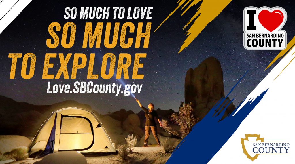 Nighttime desert camping, tent and person shining flashlight. So Much to Love, So Much to Explore, love.sbcounty.gov, I heart San Bernardino County logo, county logo.