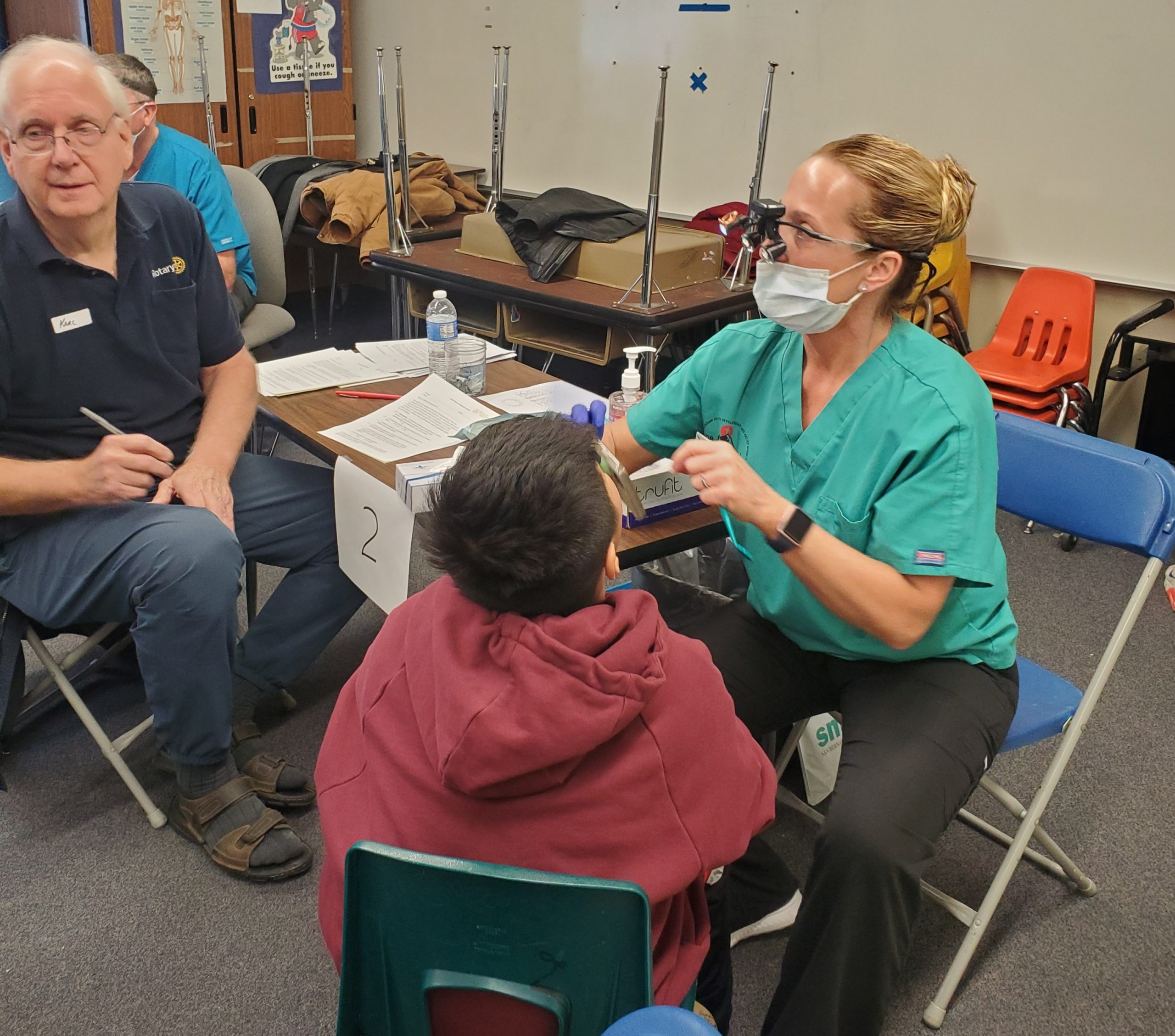 Dental professional consulting with a student during an exam.