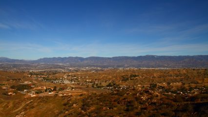 A wide view of Reche Canyon featuring hills and houses surrounded by mountains.
