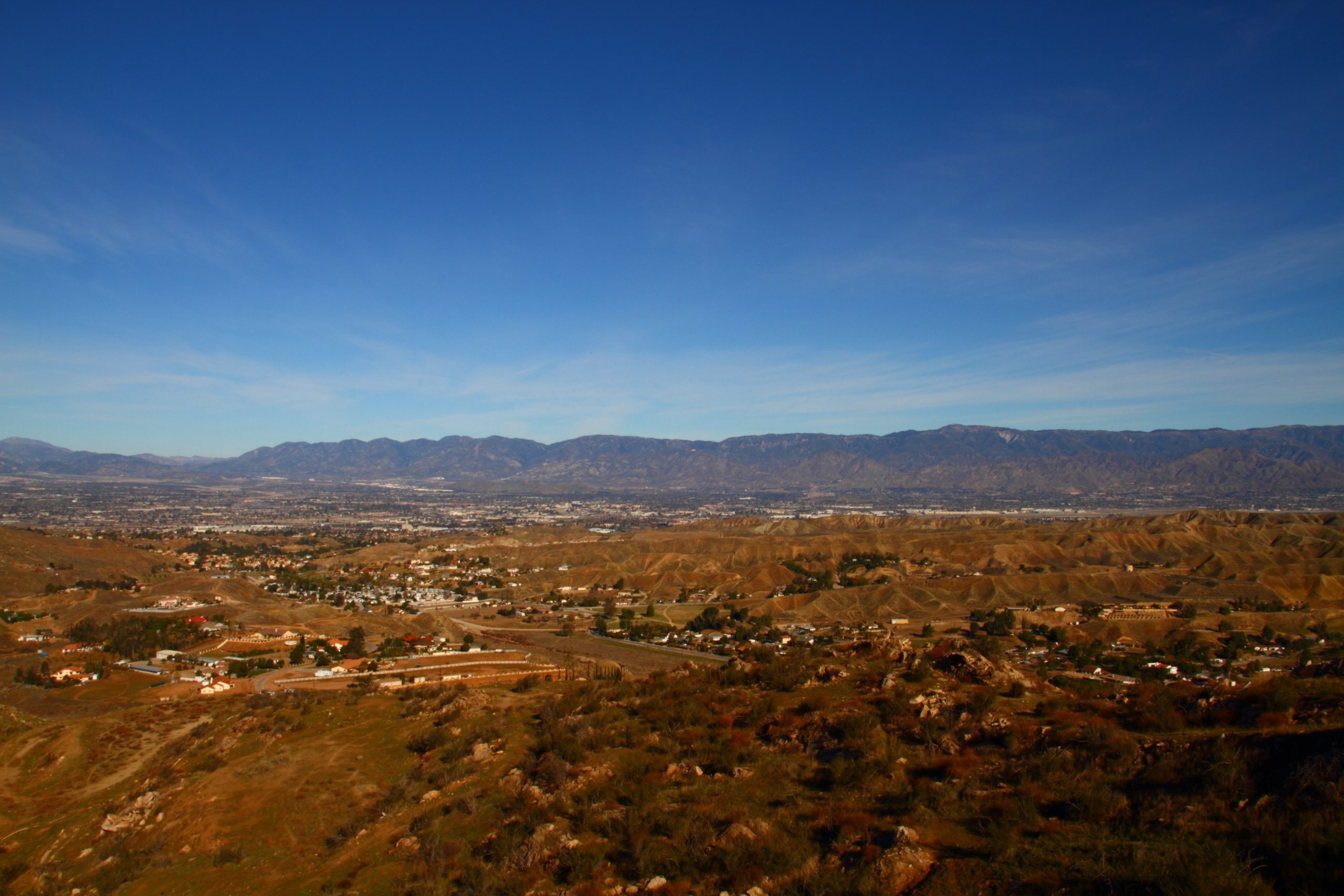 A wide view of Reche Canyon featuring hills and houses surrounded by mountains.