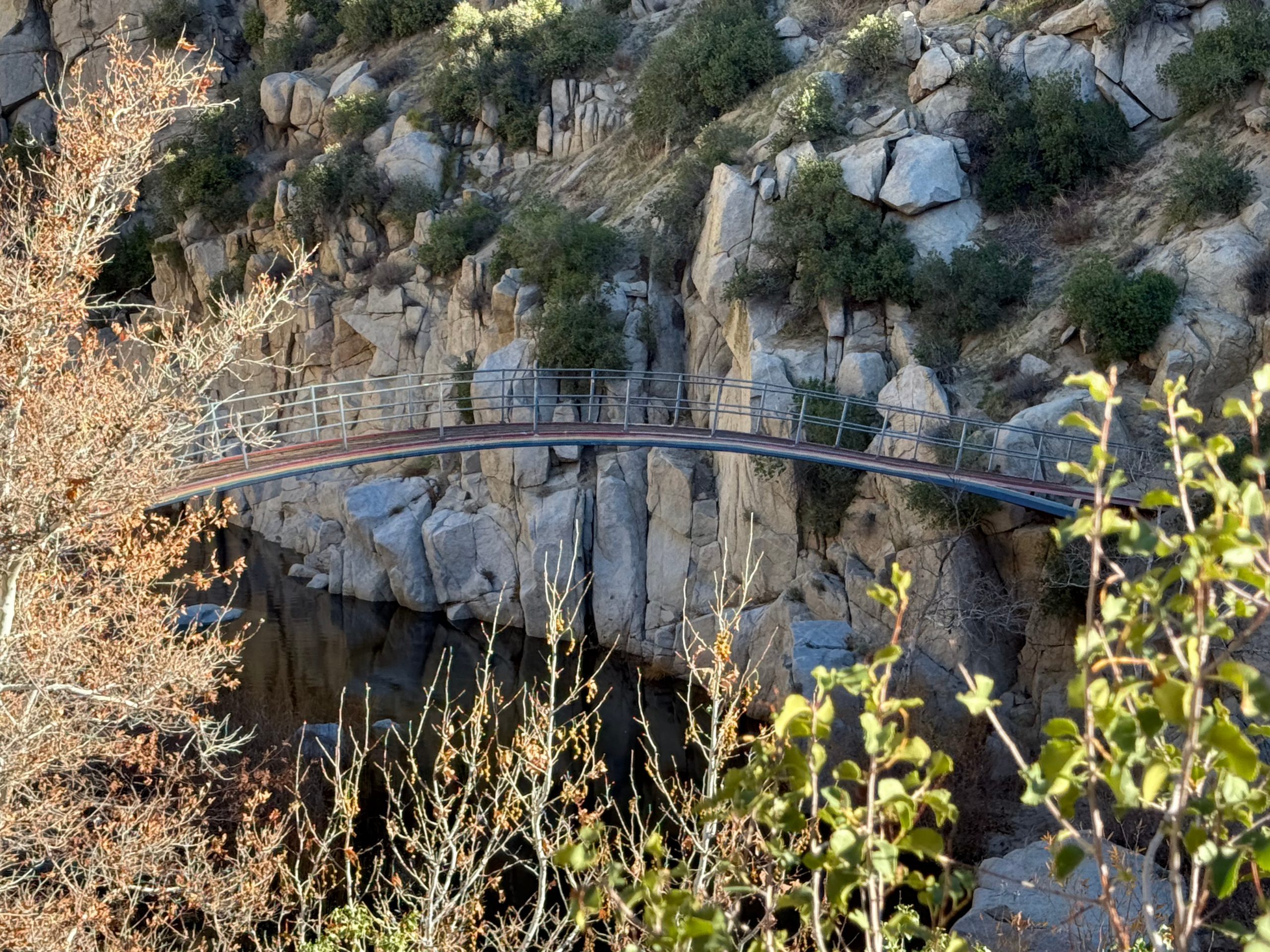A narrow pedestrian bridge that spans across rocky walls.