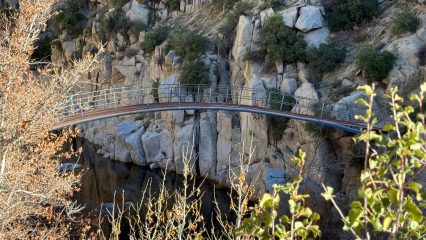 A narrow pedestrian bridge that spans across rocky walls.