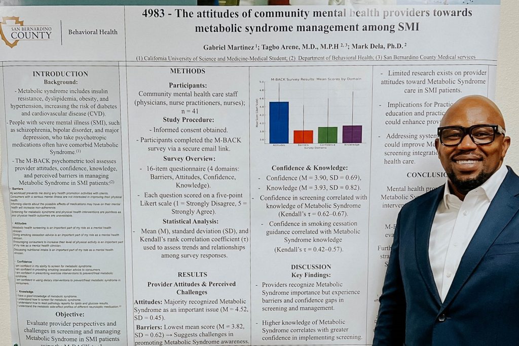 Smiling man in a suit stands beside a research poster on mental health providers’ attitudes toward metabolic syndrome management in severe mental illness patients.