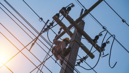 The power lineman uses an insulated tool to open the connection of the transformer from the high voltage distribution system