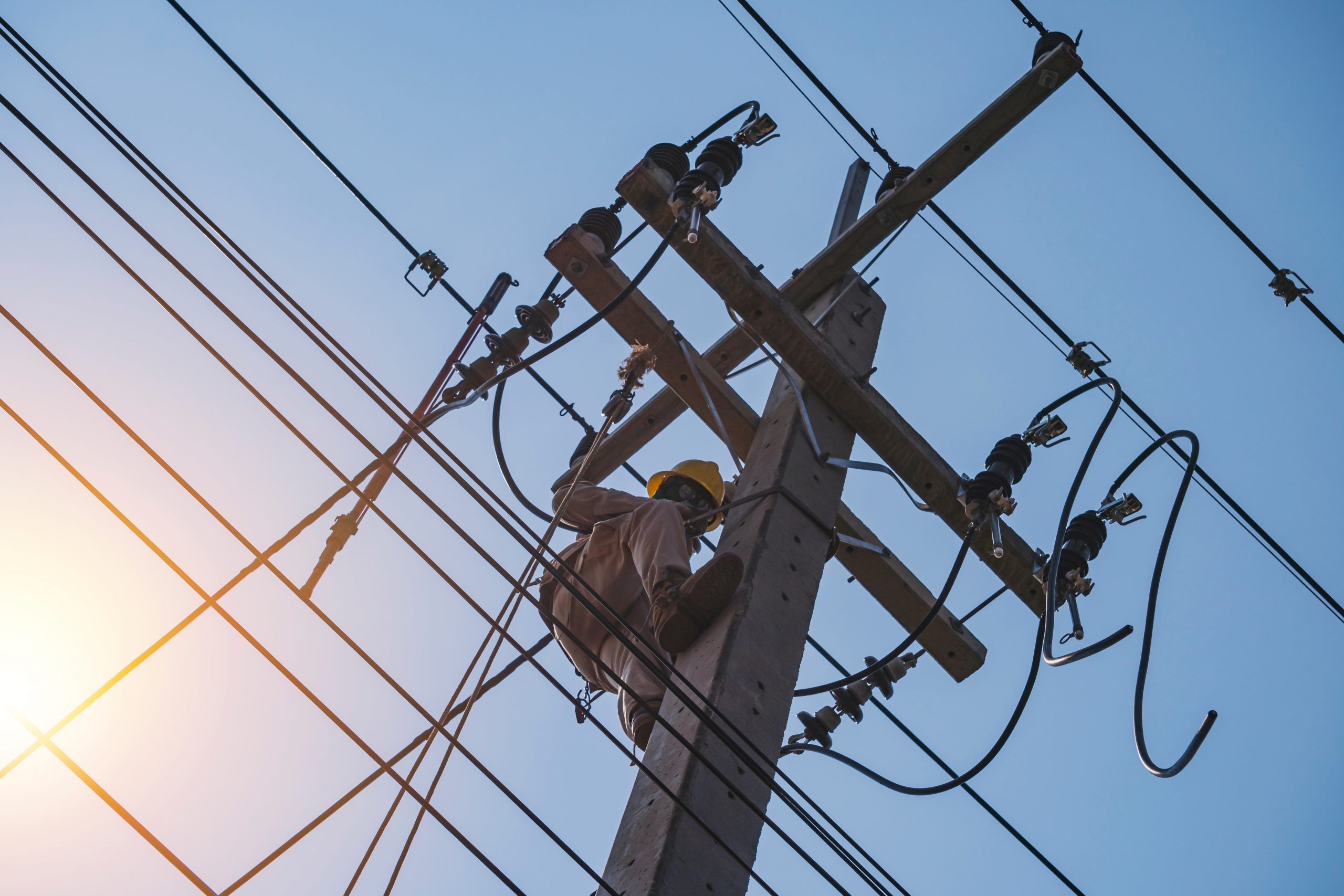 The power lineman uses an insulated tool to open the connection of the transformer from the high voltage distribution system