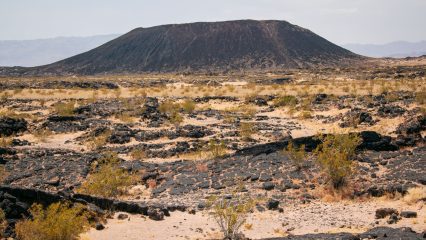 A picture of Amboy Crater in the Mojave Desert featuring a volcanic cone surrounded by lava fields.