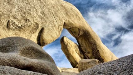 Arch shaped rock formation under a blue sky.