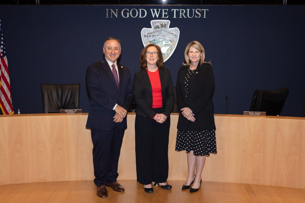 Baca, Jr., Decker, and Rowe pose in the Government Center’s Covington Chambers, standing in front of the county seal.