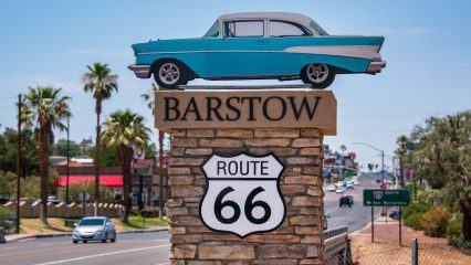 A vintage blue car mounted on a stone pillar with "Barstow Route 66" sign.