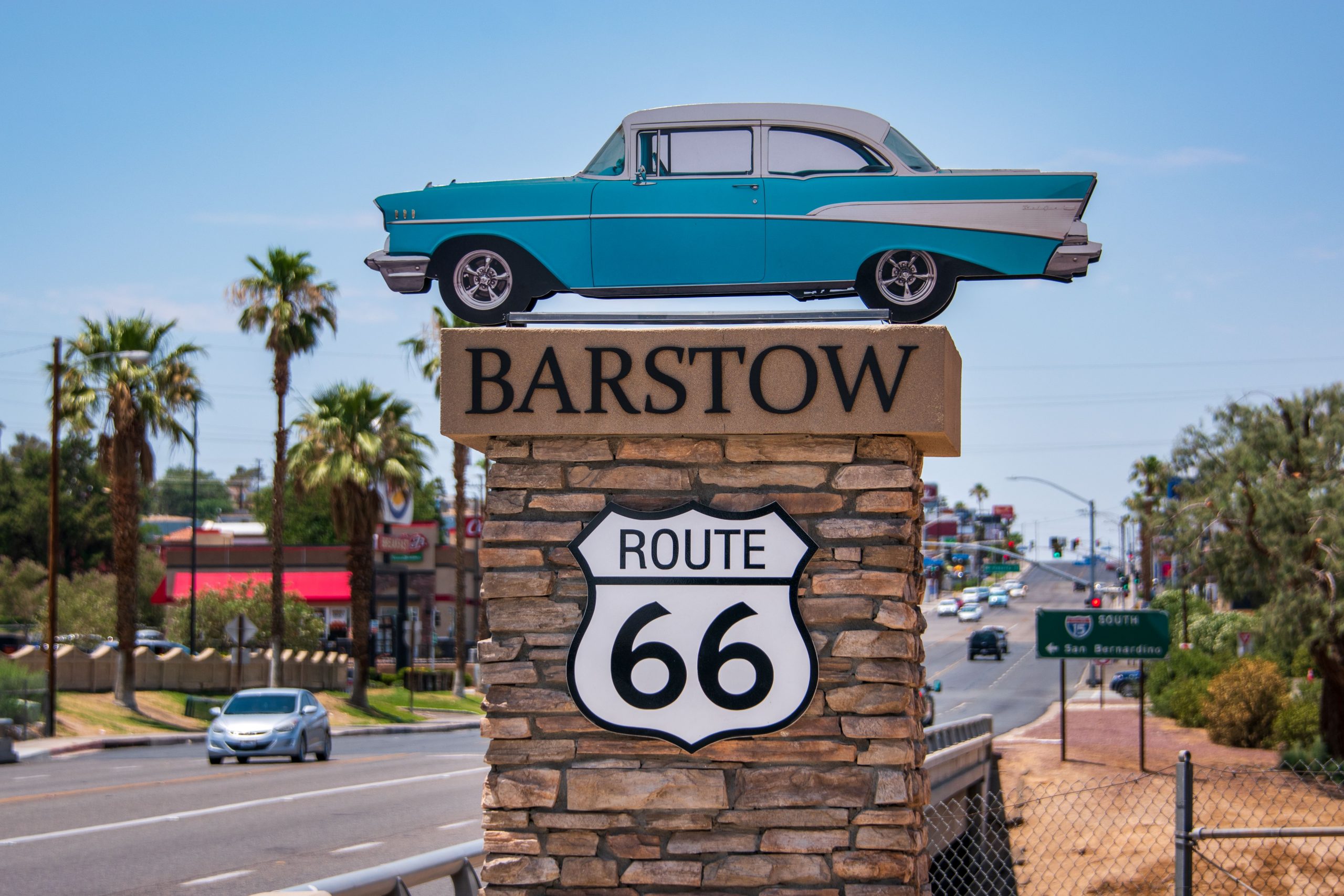A vintage blue car mounted on a stone pillar with "Barstow Route 66" sign.