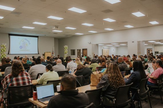 Attendees sit at long tables in a conference room during the May 2024 Behavioral Health Commission meeting.