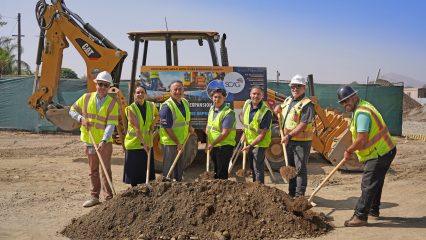 County officials and project partners hold shovels during a ceremonial groundbreaking at a construction site while wearing safety vests and hard hats.