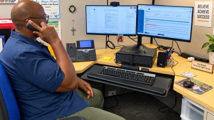 Social Service Practitioner Brian Jones speaks by phone at his workstation while viewing the DAAS Safety Response system on dual monitors.