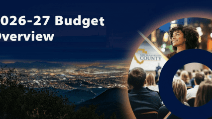 2026-27 Budget Overview text over a night cityscape; circular graphic shows a speaker addressing an audience and a smiling woman above.