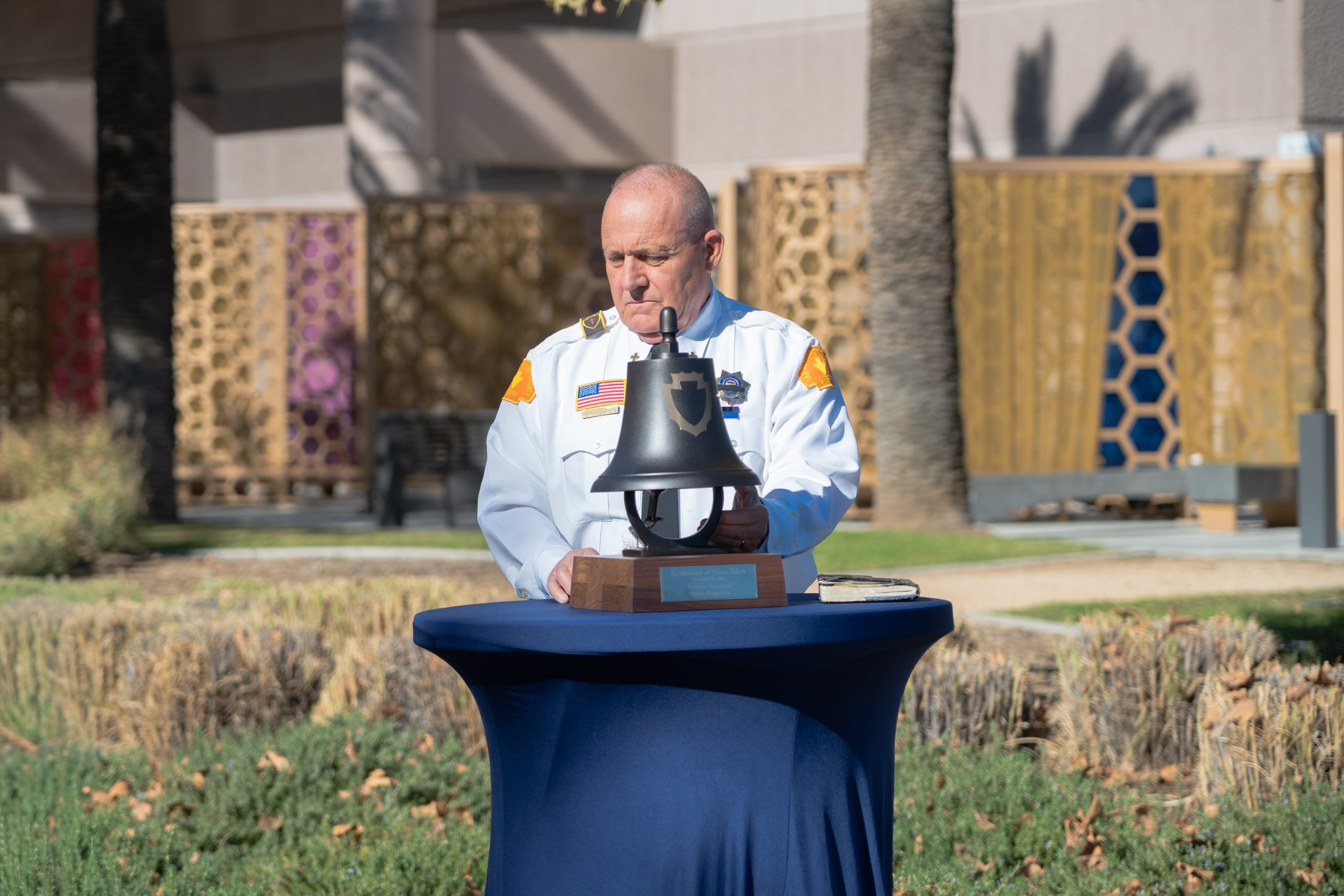 A man stands behind a table with a bell on it.