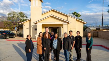 Group of ten individuals standing in front of a chapel.