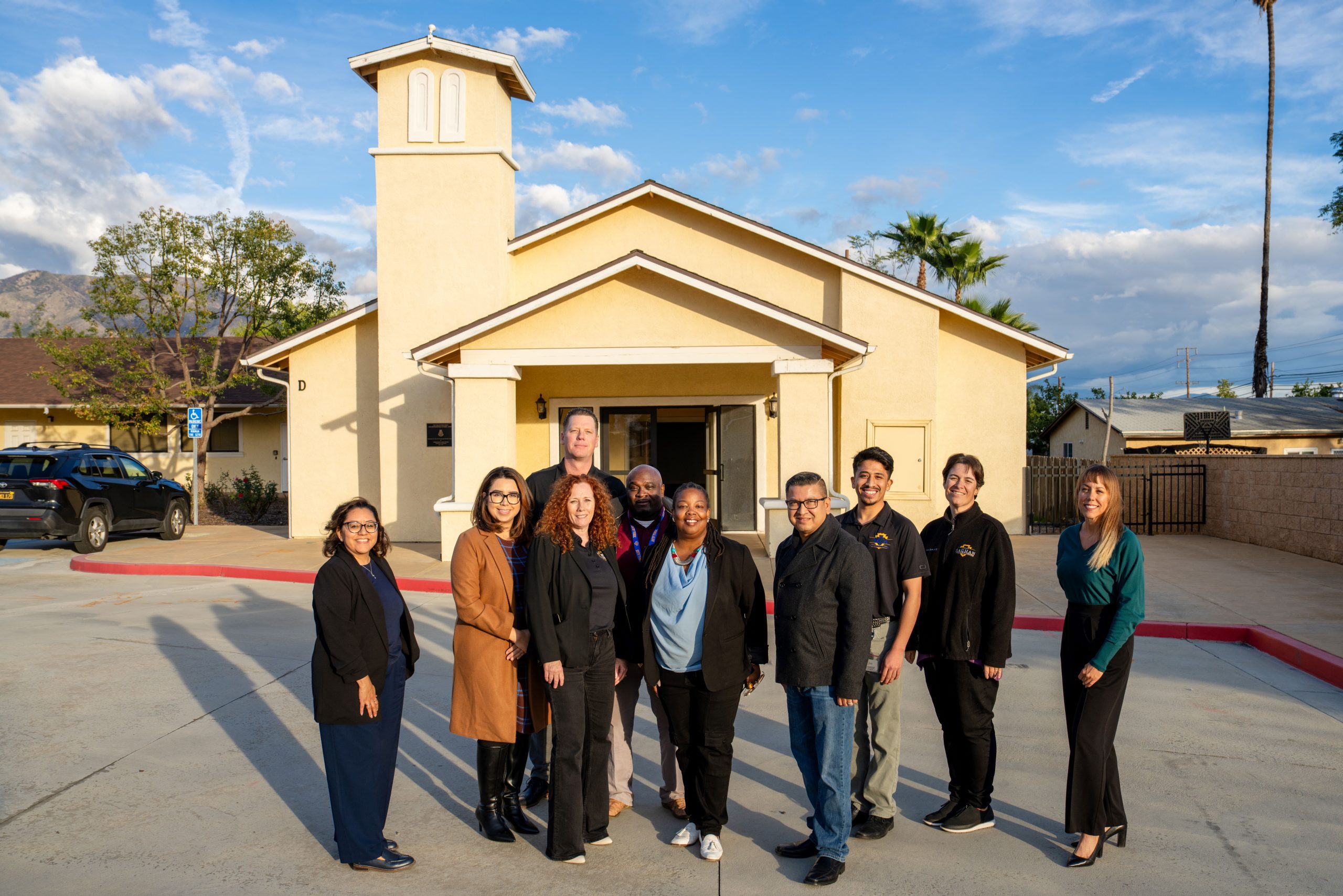 Group of ten individuals standing in front of a chapel.