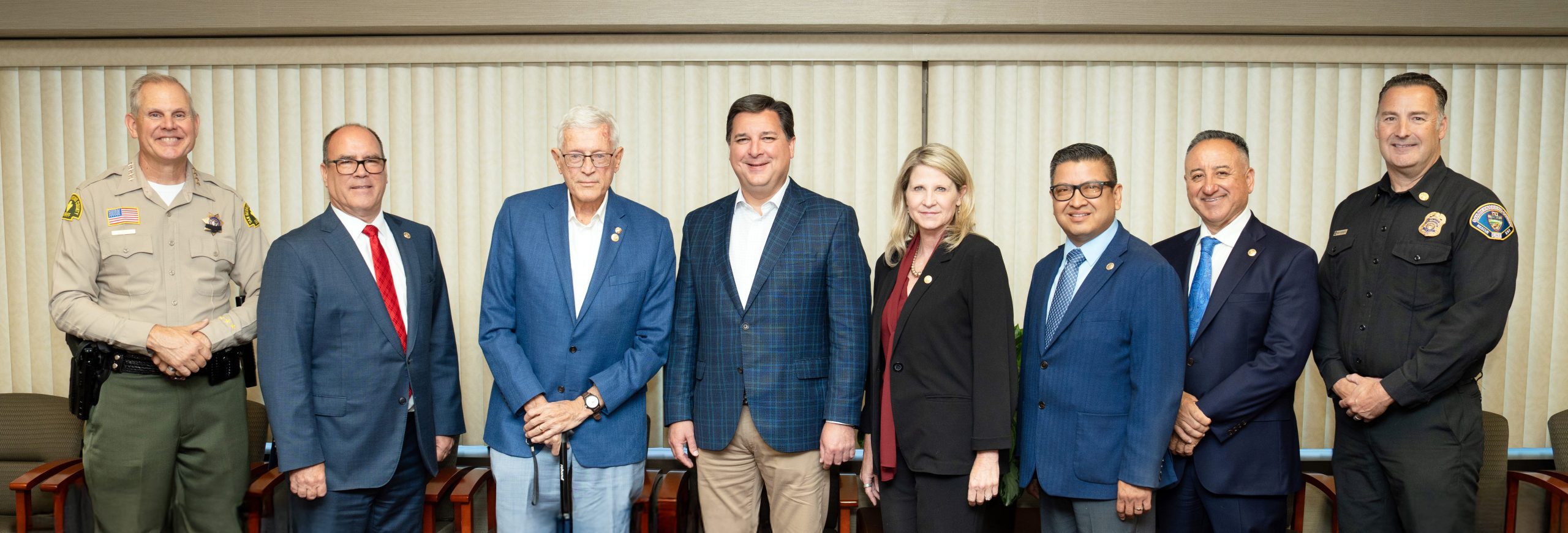 Group photo of eight individuals standing in a meeting room.