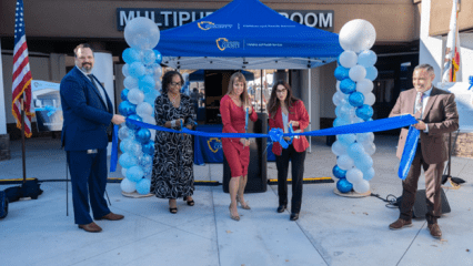 County officials stand in front of the new Highland Campus building, cutting a ceremonial ribbon to mark its official opening.