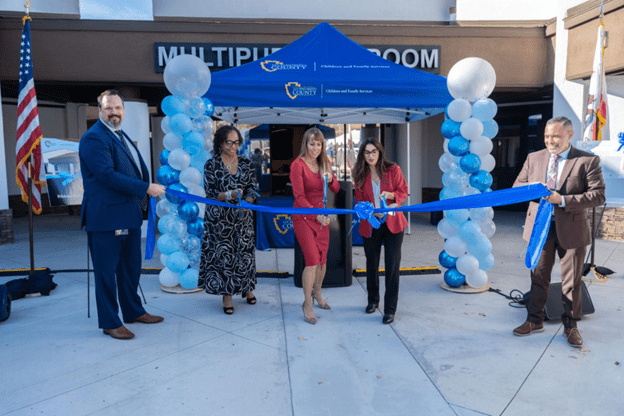 County officials stand in front of the new Highland Campus building, cutting a ceremonial ribbon to mark its official opening.
