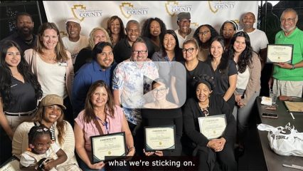 A group of people sitting and standing holding certificates.