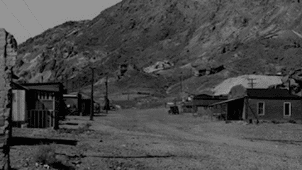 Black and white image of Calico Ghost Town with wooden buildings and mountains in the background.