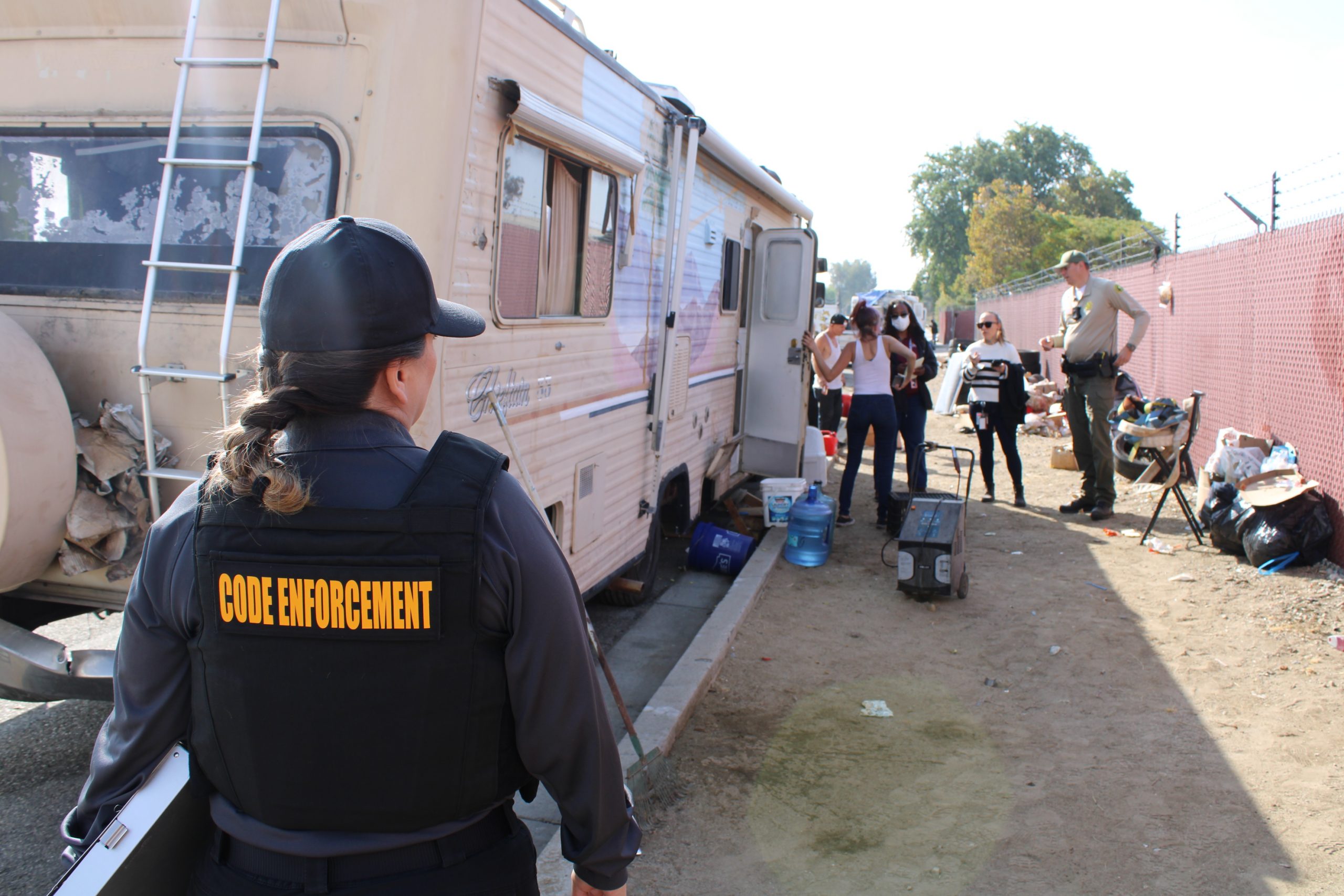 Code Enforcement Operation Photo 2 San Bernardino County Code Enforcement Officers and Sheriff's Department representative speak with individuals in front of an RV.