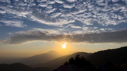 Sunset over the mountains with clouds in the sky.