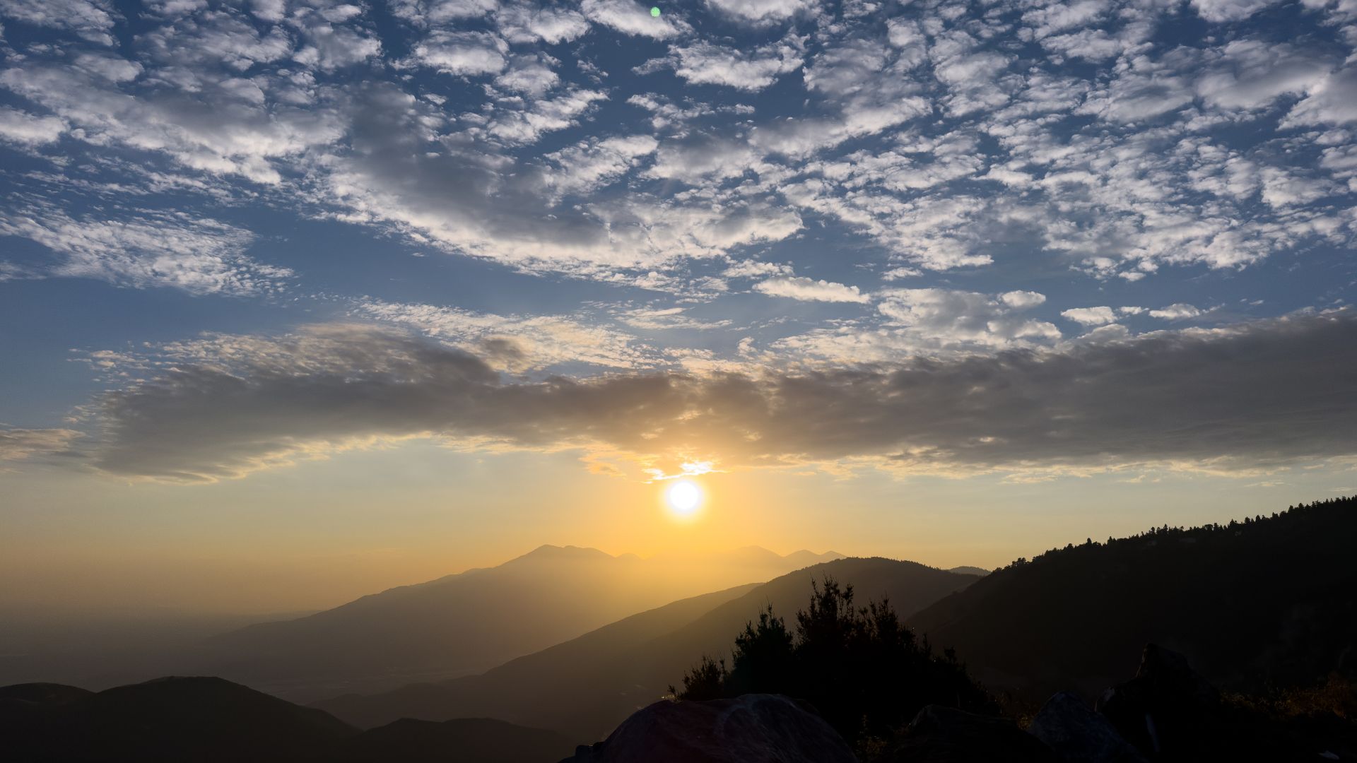 Sunset over the mountains with clouds in the sky.