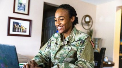 A person in military uniform using a computer.
