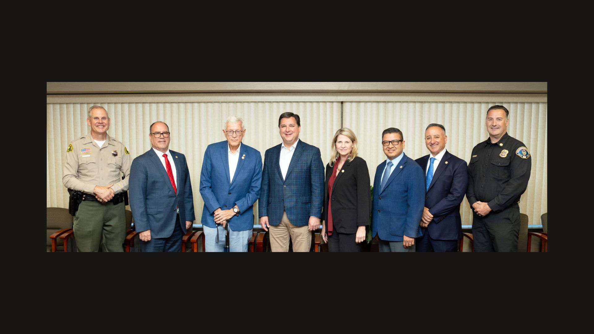 Group photo of eight individuals standing in a meeting room.