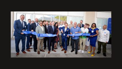 A group of professionals holding a ribbon at a ribbon-cutting ceremony.