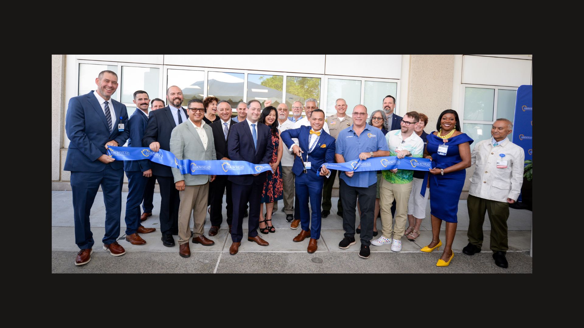 A group of professionals holding a ribbon at a ribbon-cutting ceremony.