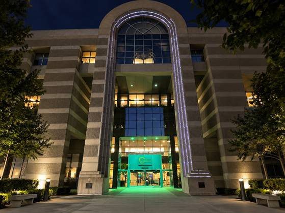 A tall building at night with the San Bernardino County logo and the front entrance illuminated green.