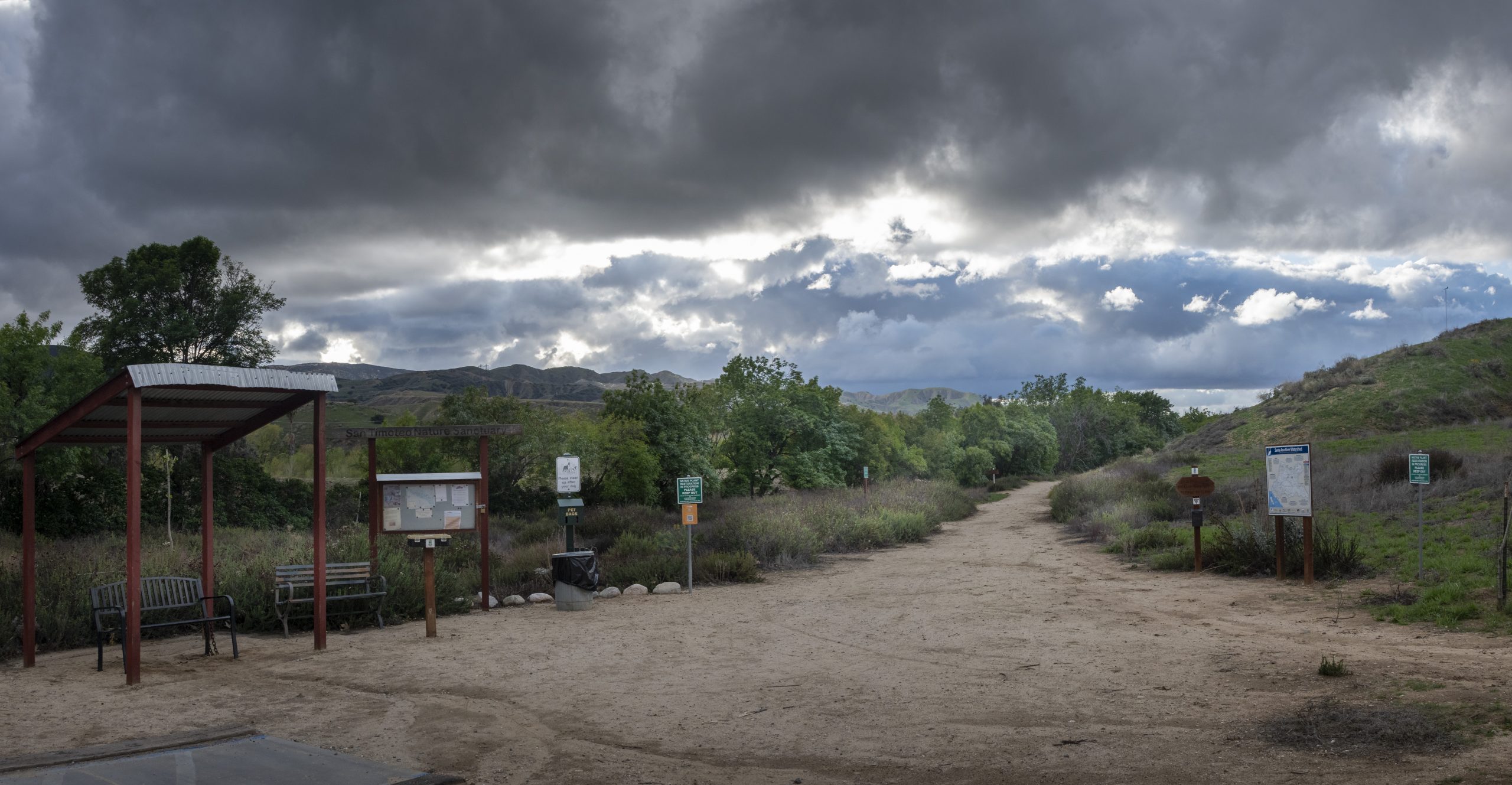 The entrance of Carriage Trail with informational boards, benches, and signage in the background