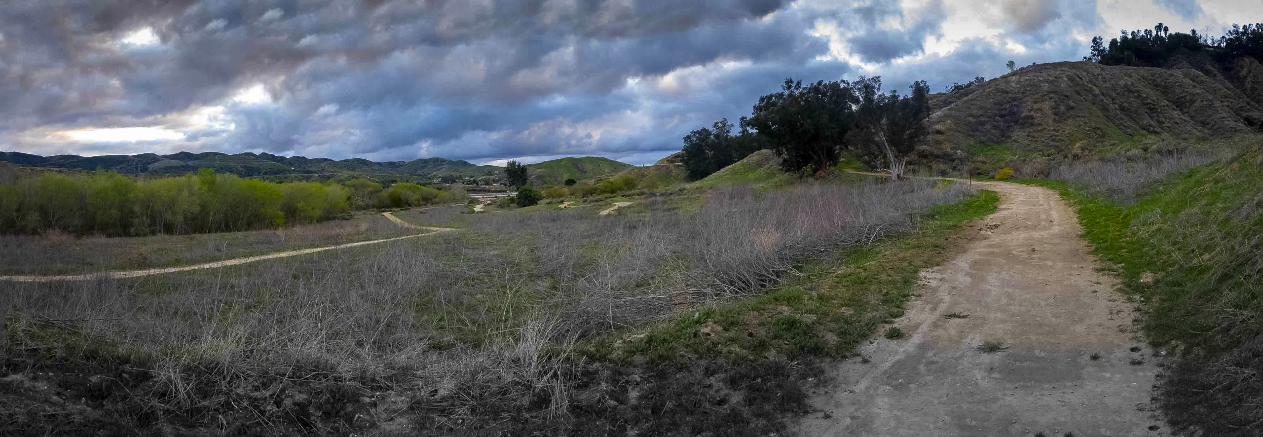 A hiking trail surrounded by hills on a cloudy day.
