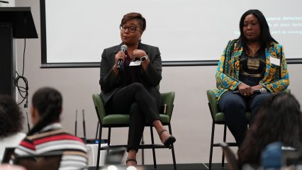 Two women on stage speak during a Provider Day Summit panel on racial bias and Black maternal mental health.