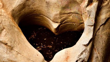 A heart-shaped hollow in a large rock that is partially filled with water.