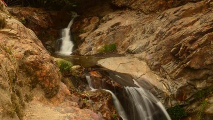 A waterfall flowing over brown rocks.